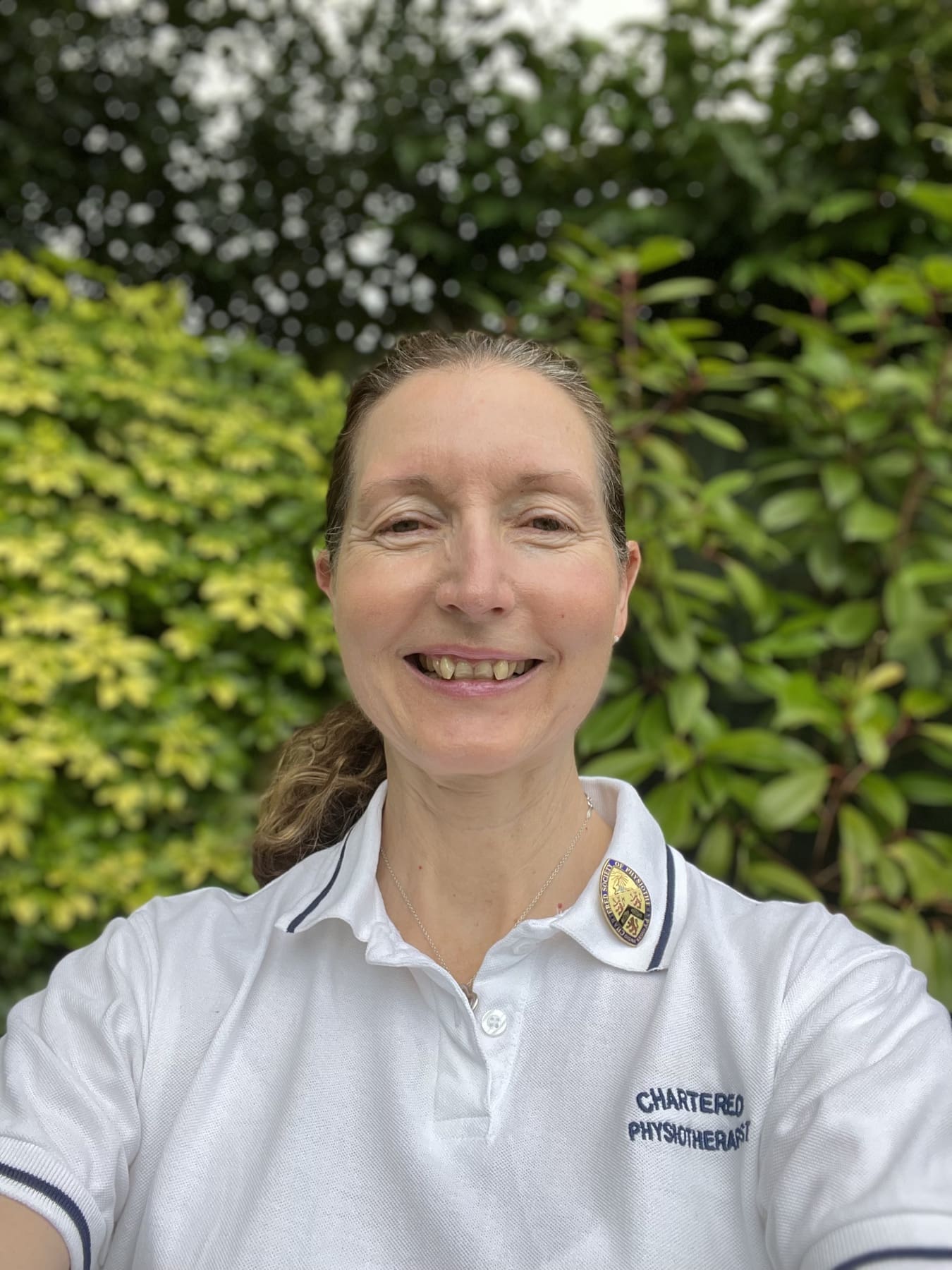 Lucy Purrier smiling in her Chartered Physiotherapist polo shirt.